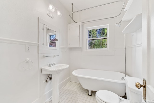 bathroom featuring a freestanding tub, a sink, and toilet