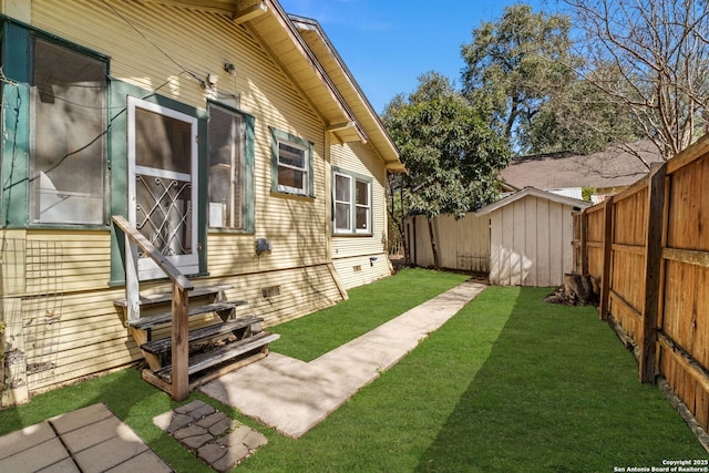 view of yard featuring entry steps, a fenced backyard, a shed, and an outbuilding