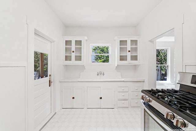 kitchen featuring gas range, white cabinets, light countertops, and light floors