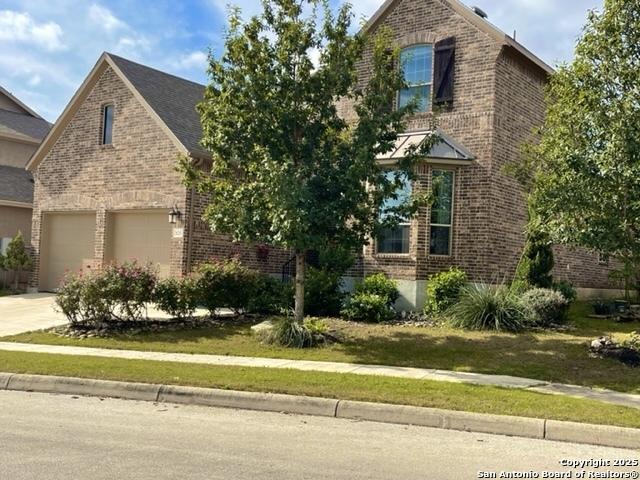 view of front of property featuring concrete driveway, brick siding, a front lawn, and an attached garage