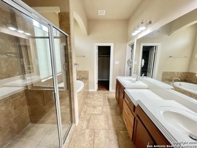 bathroom with double vanity, a garden tub, a shower stall, and a sink