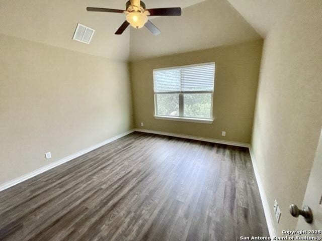 spare room featuring baseboards, visible vents, lofted ceiling, dark wood-style floors, and ceiling fan