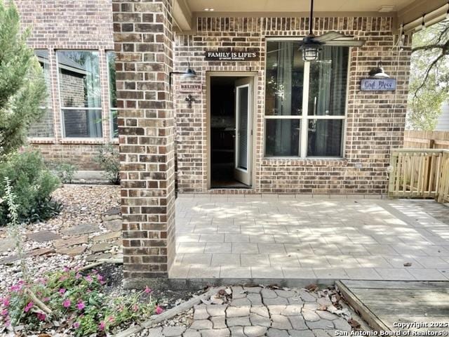 view of exterior entry featuring a patio area and brick siding