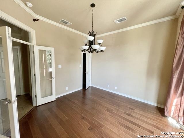 empty room featuring visible vents, a notable chandelier, and wood finished floors