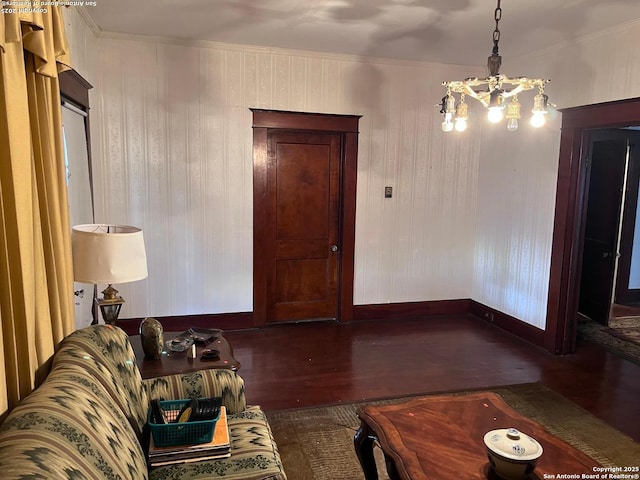 living room featuring dark wood-style flooring, a notable chandelier, crown molding, and baseboards