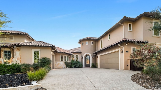 mediterranean / spanish-style home with driveway, a tile roof, a garage, and stucco siding