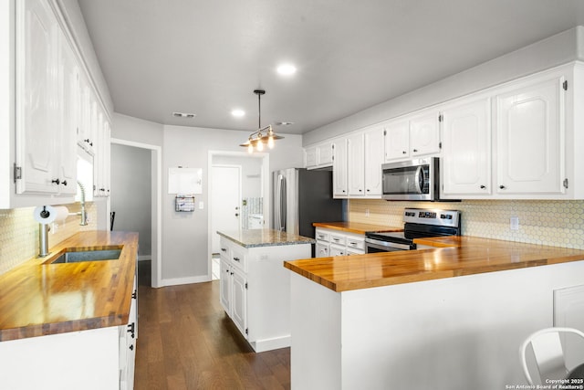 kitchen featuring stainless steel appliances, butcher block counters, a sink, white cabinets, and dark wood-style floors