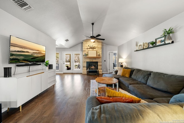 living area with dark wood-style flooring, a fireplace, visible vents, a ceiling fan, and vaulted ceiling