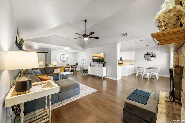 living area with visible vents, lofted ceiling, ceiling fan, dark wood-style flooring, and a fireplace