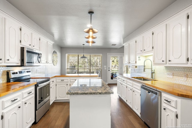 kitchen featuring appliances with stainless steel finishes, white cabinetry, a sink, and a peninsula