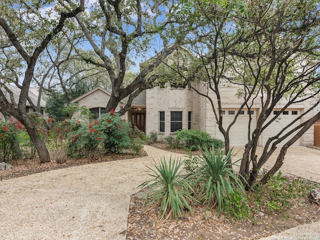 view of front of home featuring driveway, a garage, and brick siding