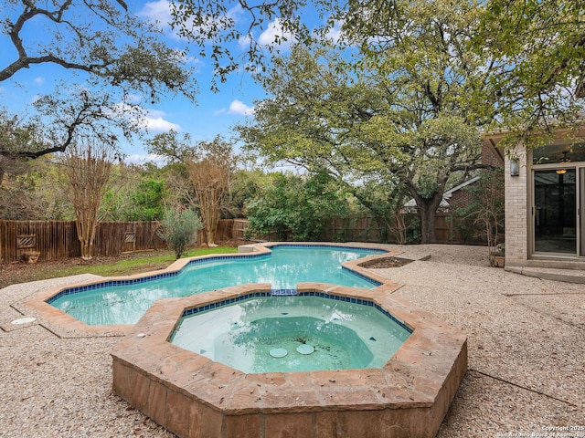 view of pool with a fenced backyard and a pool with connected hot tub