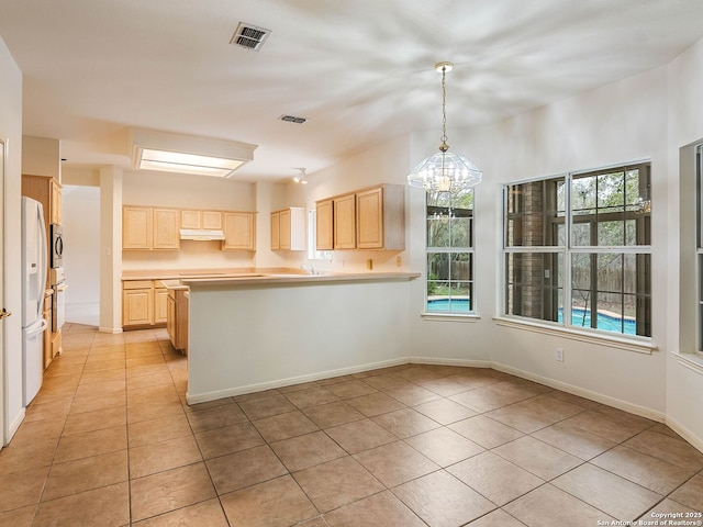 kitchen with light tile patterned floors, light brown cabinetry, visible vents, and under cabinet range hood