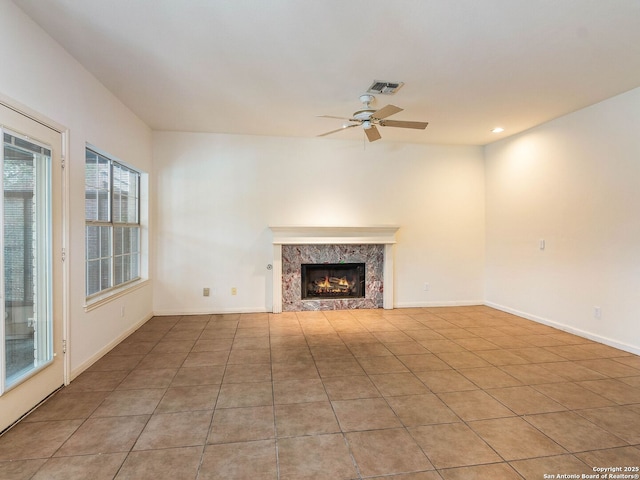 unfurnished living room featuring a fireplace, visible vents, a ceiling fan, light tile patterned flooring, and baseboards