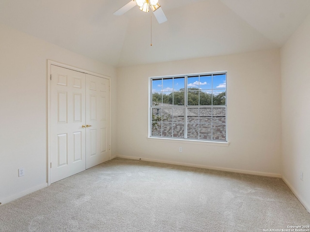 unfurnished bedroom with carpet, lofted ceiling, a closet, ceiling fan, and baseboards