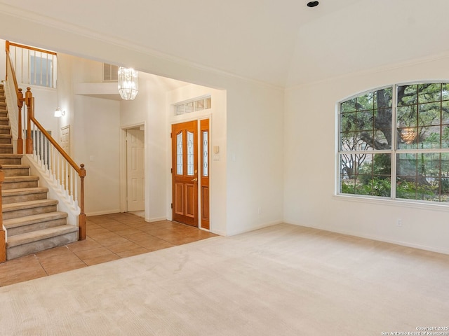 carpeted entryway with lofted ceiling, visible vents, stairs, tile patterned floors, and an inviting chandelier