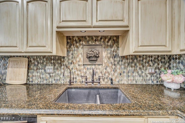 kitchen with tasteful backsplash, a sink, and dark stone countertops