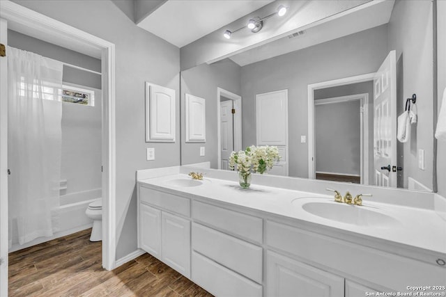 full bath with double vanity, wood finished floors, a sink, and visible vents