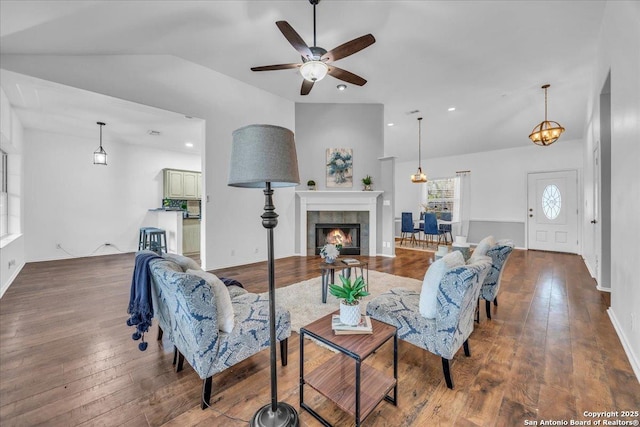 living room with baseboards, a tile fireplace, lofted ceiling, hardwood / wood-style floors, and recessed lighting