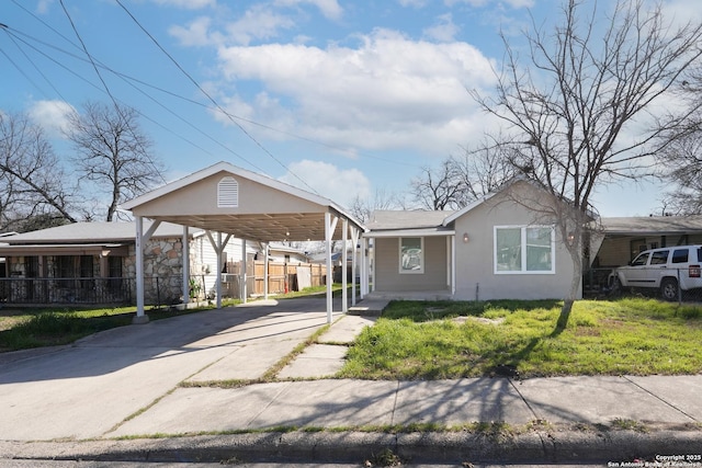 view of front facade with fence, concrete driveway, stucco siding, a carport, and a front lawn