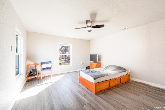 bedroom featuring baseboards, visible vents, ceiling fan, and wood finished floors