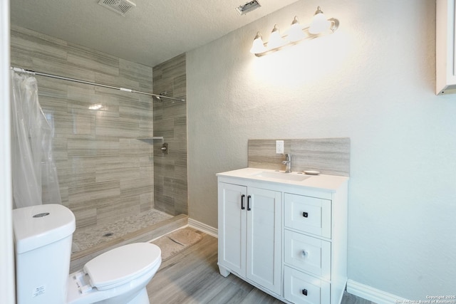 bathroom featuring toilet, visible vents, and a tile shower