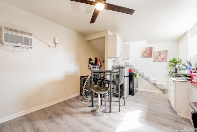 interior space featuring a wall unit AC, light wood-type flooring, and baseboards