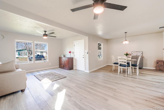 living area featuring light wood finished floors, visible vents, baseboards, and a ceiling fan