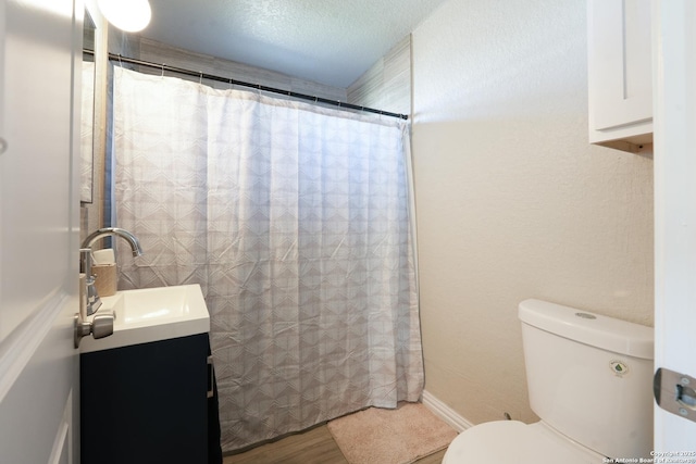 bathroom featuring a shower with shower curtain, toilet, wood finished floors, a textured ceiling, and vanity