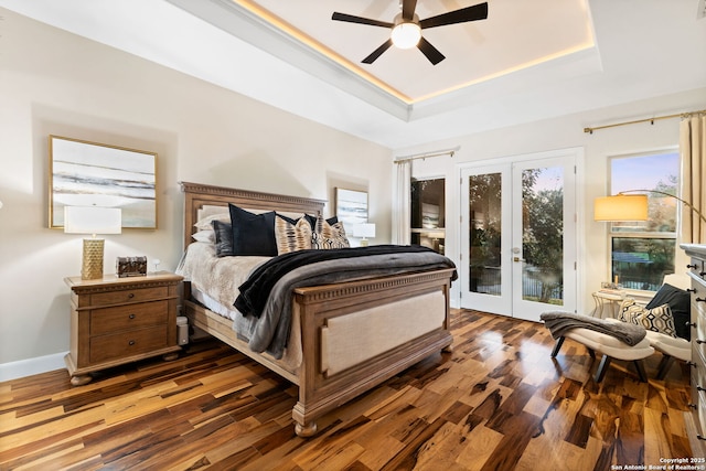 bedroom featuring a tray ceiling, access to outside, french doors, and wood finished floors