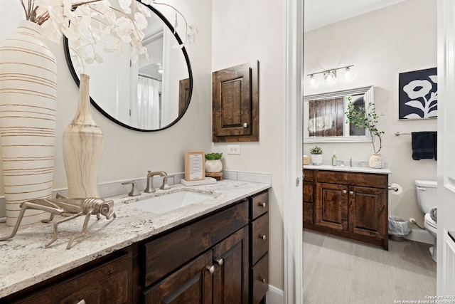 full bath with two vanities, a sink, and toilet