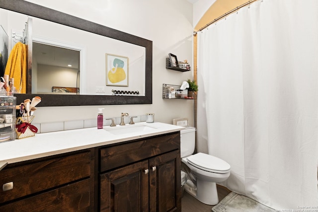 full bathroom featuring a shower with shower curtain, vanity, and toilet