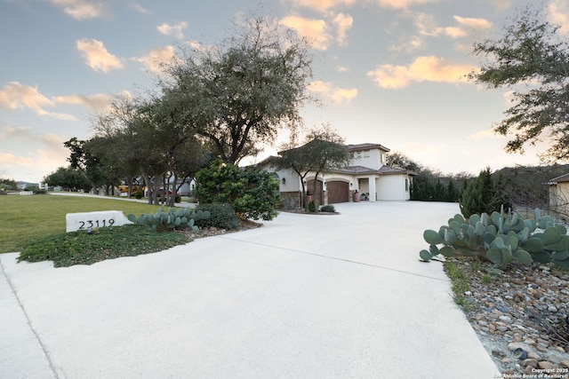 view of front of house featuring a garage, concrete driveway, and a lawn