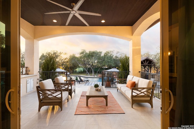 patio terrace at dusk with outdoor lounge area and ceiling fan