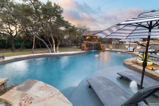 pool at dusk featuring a patio, fence, and a fenced in pool