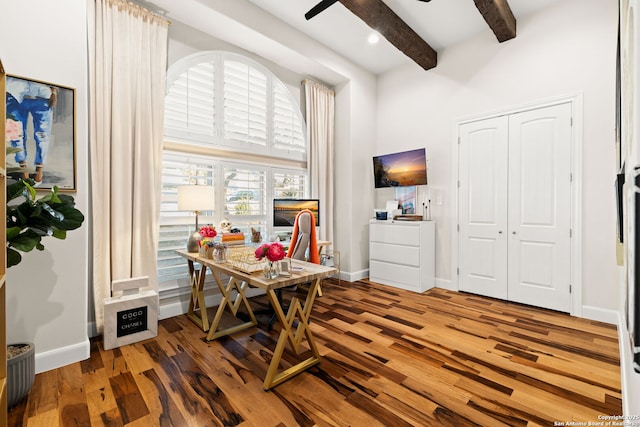 office featuring wood finished floors, a towering ceiling, a ceiling fan, baseboards, and beam ceiling