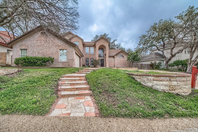 view of front of home with brick siding, a front lawn, and fence