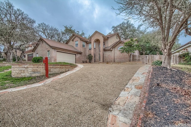 view of front facade featuring brick siding, fence, driveway, and an attached garage