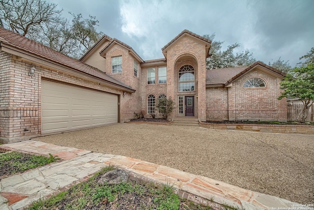 traditional home featuring a tile roof, brick siding, driveway, and an attached garage