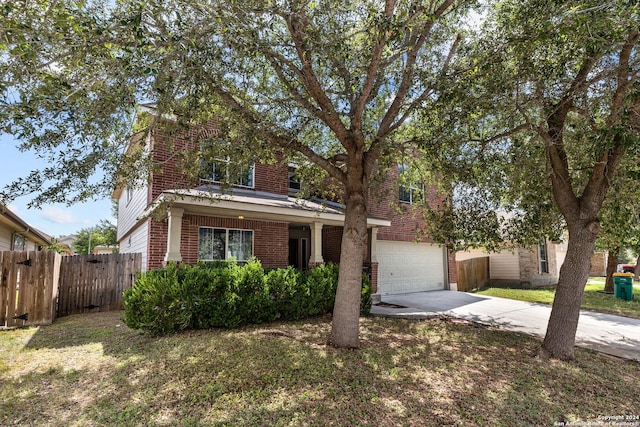 traditional-style home featuring an attached garage, brick siding, fence, concrete driveway, and a front lawn