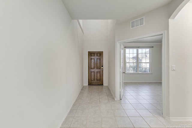 foyer entrance with light tile patterned floors, baseboards, visible vents, and arched walkways