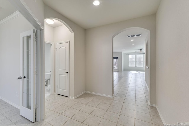 hall featuring arched walkways, light tile patterned flooring, recessed lighting, visible vents, and baseboards