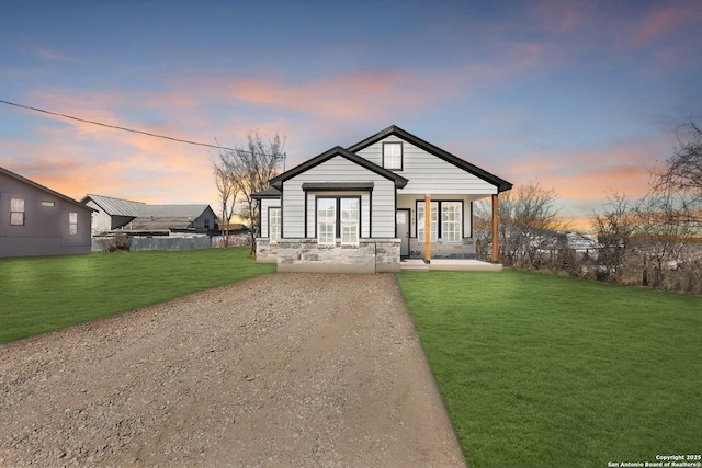 view of front of house with covered porch, stone siding, and a front yard