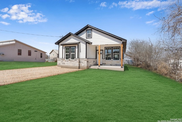 view of front facade featuring covered porch, stone siding, and a front yard