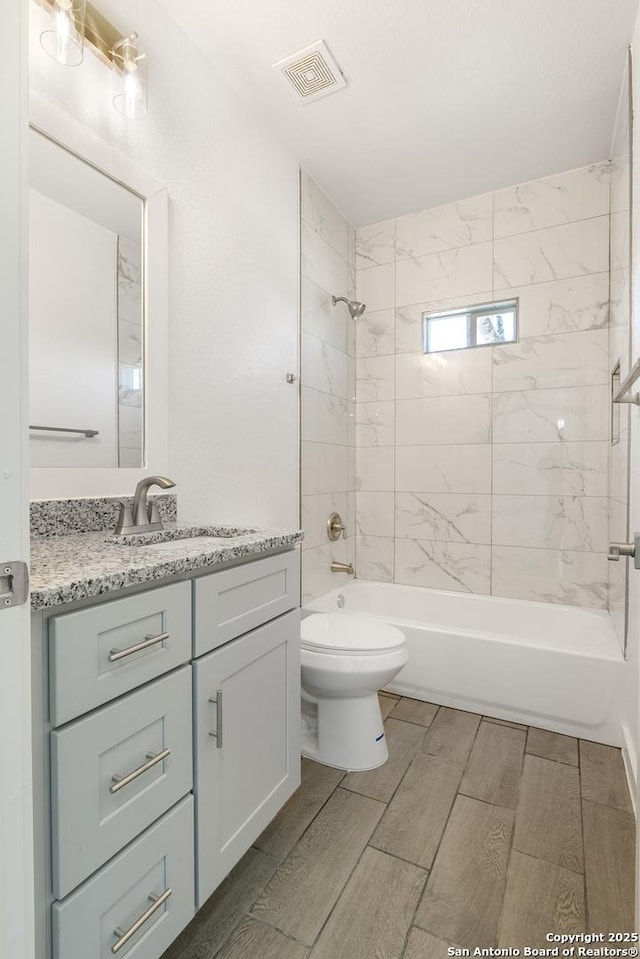 bathroom with visible vents, toilet, wood tiled floor, vanity, and shower / bathing tub combination