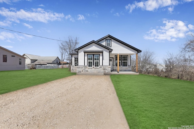 view of front facade featuring stone siding, a porch, and a front lawn