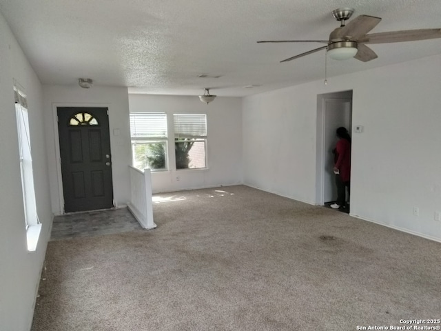 foyer with carpet, a ceiling fan, and a textured ceiling