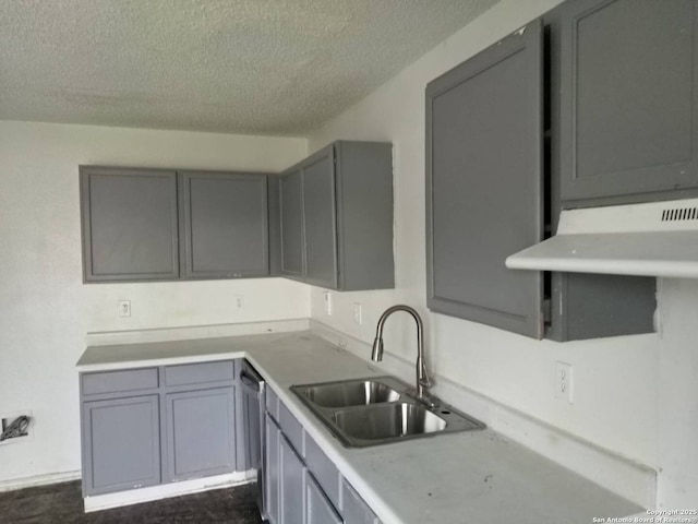 kitchen with gray cabinets, light countertops, a sink, a textured ceiling, and dishwasher