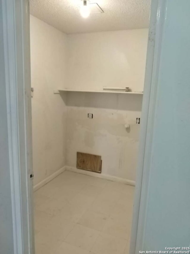 laundry room with a textured ceiling, light floors, and baseboards