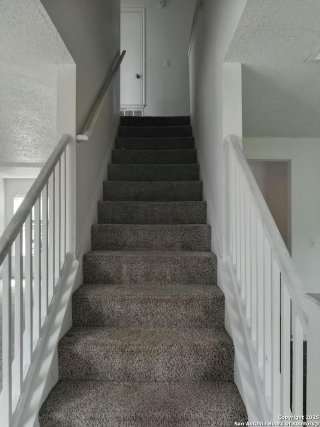 staircase featuring a textured ceiling